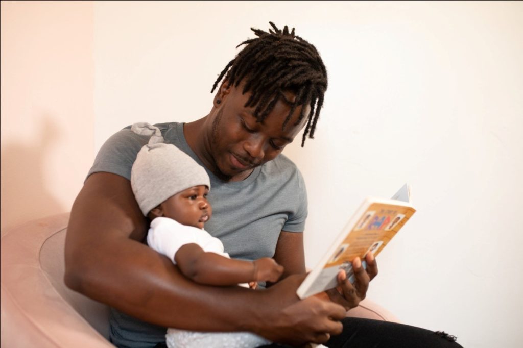 A Book Being Read to an Infant Baby by Their Father