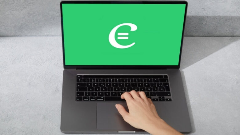 A hand rests on a laptop showing the Cymath logo on a green screen, ready to solve math problems