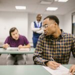 Students in a classroom taking a quiz while a teacher observes