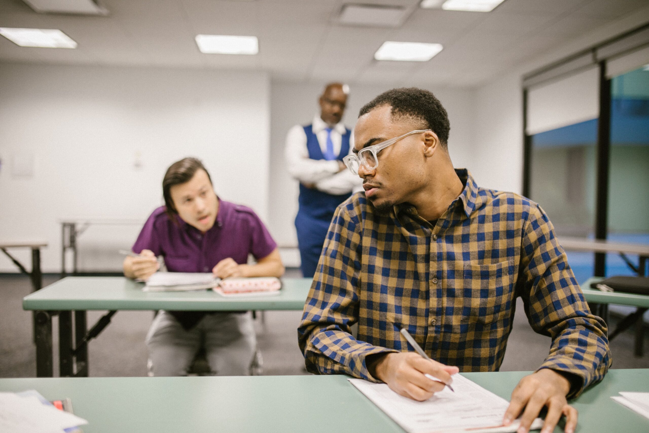 Students in a classroom taking a quiz while a teacher observes
