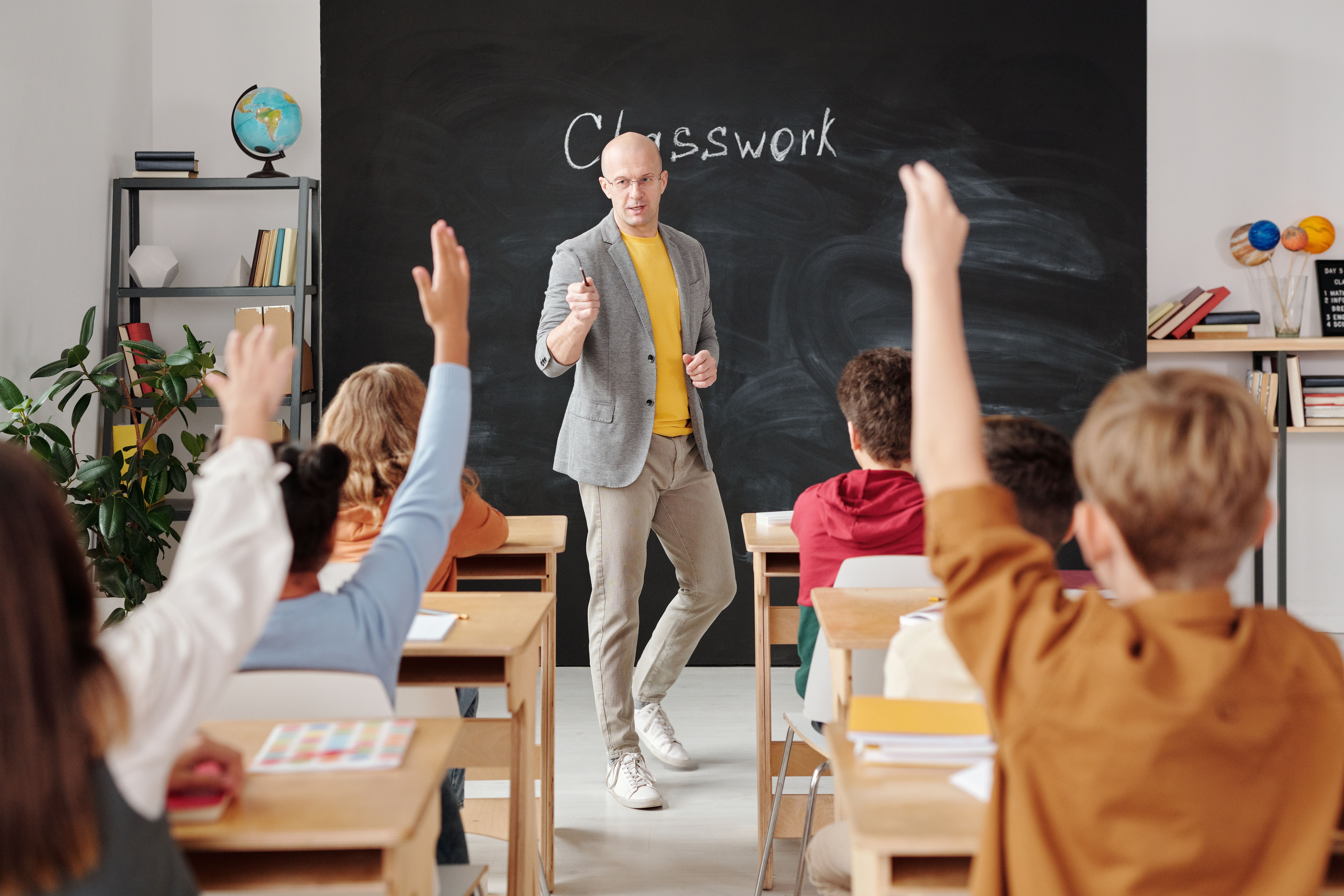 Teacher interacting with students raising hands during an engaging classroom quiz activity